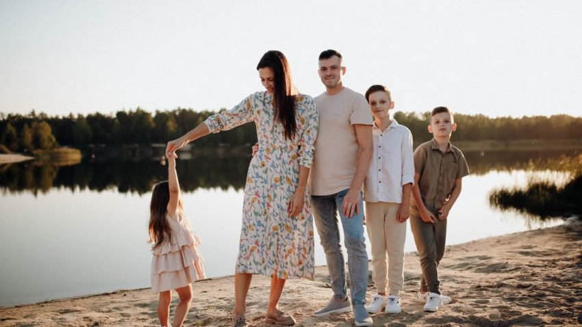 A family of five enjoys a serene lakeside vacation at sunset, capturing precious moments together.